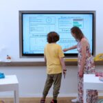 a teacher helping a pupil with an interactive screen