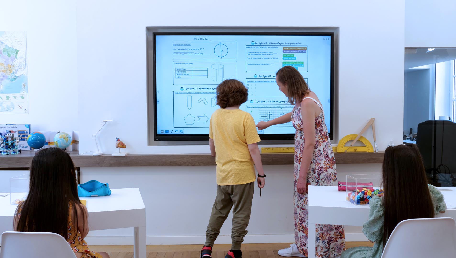 a teacher helping a pupil with an interactive screen